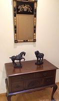 Full view of dresser with two horse sculptures and colonial style wall mirror above