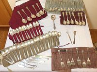 Overview of all flatware laid out in cloth rolls and loose on table