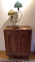 Full view of wooden cabinet topped by dual-globe lamp