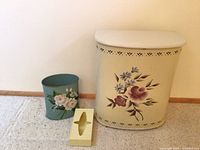Photo showing the three items: large cream-colored metal hamper, blue waste basket, and yellow tissue box on carpet against a wall.