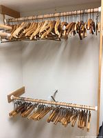 Wooden clothes hangers on closet rod, including different styles visible from front view.