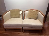 Two Lexington chairs side by side with beige fabric upholstery, curved wooden frames, and matching square pillows.