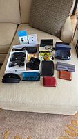 Photo shows all items arranged on sofa: multiple sunglasses, wallets, lens cleaning supplies.