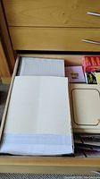 Close-up photo of printer paper, lined notepads, envelopes inside the drawer