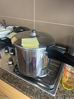 Full view of the closed pressure cooker on a stove showing stainless steel finish with lid and black handle.