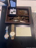 Full lot showing watches, men’s cufflinks including New Zealand Paua shell, and sterling silver tie bar on black and brown trays.