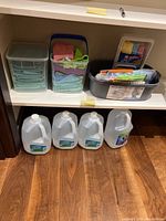 Photo showing four sealed brand new one-gallon bottles of distilled water on floor.