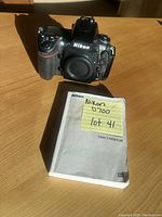 Front view of camera body with body cap installed and manual in foreground