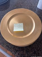 Top view of a single gold decorative charger plate showing the full round shape and textured rim.