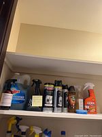 Photo showing a variety of cleaning products on a pantry shelf including Windex, Weiman stainless steel cans and wipes, Old English, Lexol, and other spray bottles.