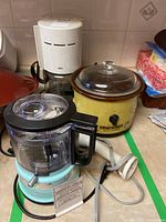 Braun coffee maker, Rival yellow crock pot, KitchenAid food chopper on counter