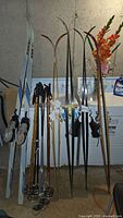 Full lot showing skis, boots mounted on skis, and ski poles in basement setting.