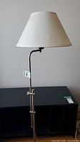 Full view of the floor lamp showing the white fabric shade and the adjustable metal pole.