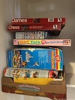 Stack of five game and puzzle boxes including Checkers, Chess, Girl Talk, Disneyland board game and Flags of the World puzzle