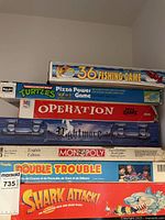 Stacked vintage board games showing titles and box conditions