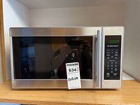 Front view of Hamilton Beach microwave with stainless steel exterior and black glass door, displaying model and brand information.