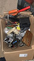 Box with assorted hand tools and hardware including drill, saw, hammer, iron, and more