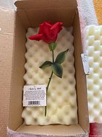 Photo of the hand painted red porcelain rose with stem inside protective foam packaging and cardboard box.
