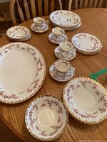 Full set displayed on table showing plates, bowls, cups, saucers, and platter