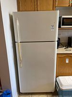 Front view of white Sears refrigerator with visible wear on door handles and surfaces in a kitchen area.