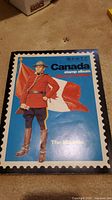 Close-up photo of Scott Canada stamp album showing Mountie with flag on cover.