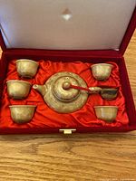 Full view of the teapot and six teacups arranged inside the red velvet-lined box.