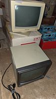 Two vintage monitors stacked, beige Intra monitor on top and darker Packard Bell monitor below