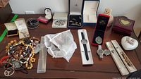 Wide view of table showing assorted jewelry clusters, watches in boxes, and decorative boxes