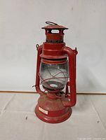 Photo of a red antique oil lantern with metal frame and glass chimney