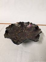 Side angled view showing the scalloped edge and leaf pattern with iridescent colors.