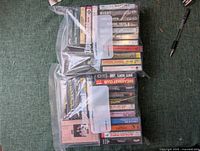 Photo of a collection of vintage cassette tapes stacked and bundled in plastic sleeves on a green surface.