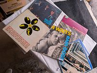 Five vintage vinyl records laid out on a surface, showing various album covers including The Rolling Stones.