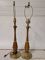 Photo showing pair of Mid-Century Modern teak and brass table lamps with wiring and bulb sockets visible