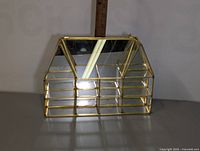 Mini glass display cabinet with gold metal frame and several compartments, viewed from front with ruler showing height.