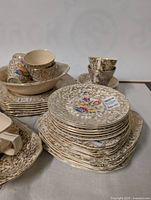 Photo of stacked plates with floral and gold pattern, showing details on the plates and cups on top