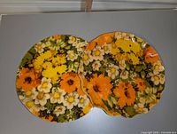 Two vintage serving trays with floral patterns, one round and one scalloped.