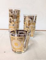 Front view of stacked set of eight Libbey glasses showing gold geometric and medallion design