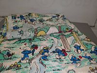 Two single bed coverlets featuring Smurf characters laid out to show print and design.