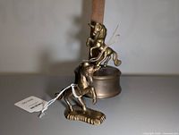 Two brass unicorn figurines placed together with ruler in background to show size. One is atop a round brass music box, the other on a flat base.