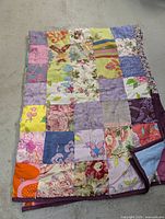 Front view showing patchwork design of multiple fabric squares in pastel and floral patterns