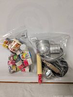 Photo of two plastic bags; one containing small vintage toy food cans and the other containing vintage kids kitchen tools.