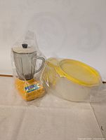 Photo of vintage kids toy blender and Tupperware container wrapped in clear plastic.