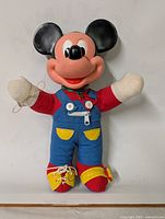 Front view of vintage Mickey Mouse plush toy, showing facial details, overalls, and shoes