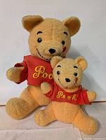 Two vintage Winnie the Pooh plush bears seated side by side with visible front view.