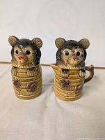 Front view of vintage ceramic bear salt and pepper shakers showing bear heads as lids and beehive-shaped containers with floral designs.