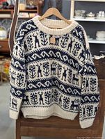 Full front view of wool sweater on hanger showing cream and dark blue Nordic pattern design.