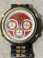 Close-up of watch face showing red dial, three subdials, Ferrari logo, and tachymeter scale