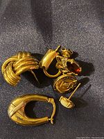 Assorted gold jewelry pieces arranged on dark fabric