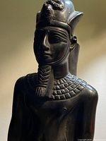 Close-up photo showing detailed facial features, headdress, and collar of the Egyptian Pharaoh sculpture.