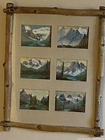 Full view of the folk art branch wood framed six scenic paintings showing lakes and mountains.
